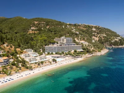 Luchtfoto van het strand van Nissaki aan de noordoostkust van Corfu met hotels tussen het groen