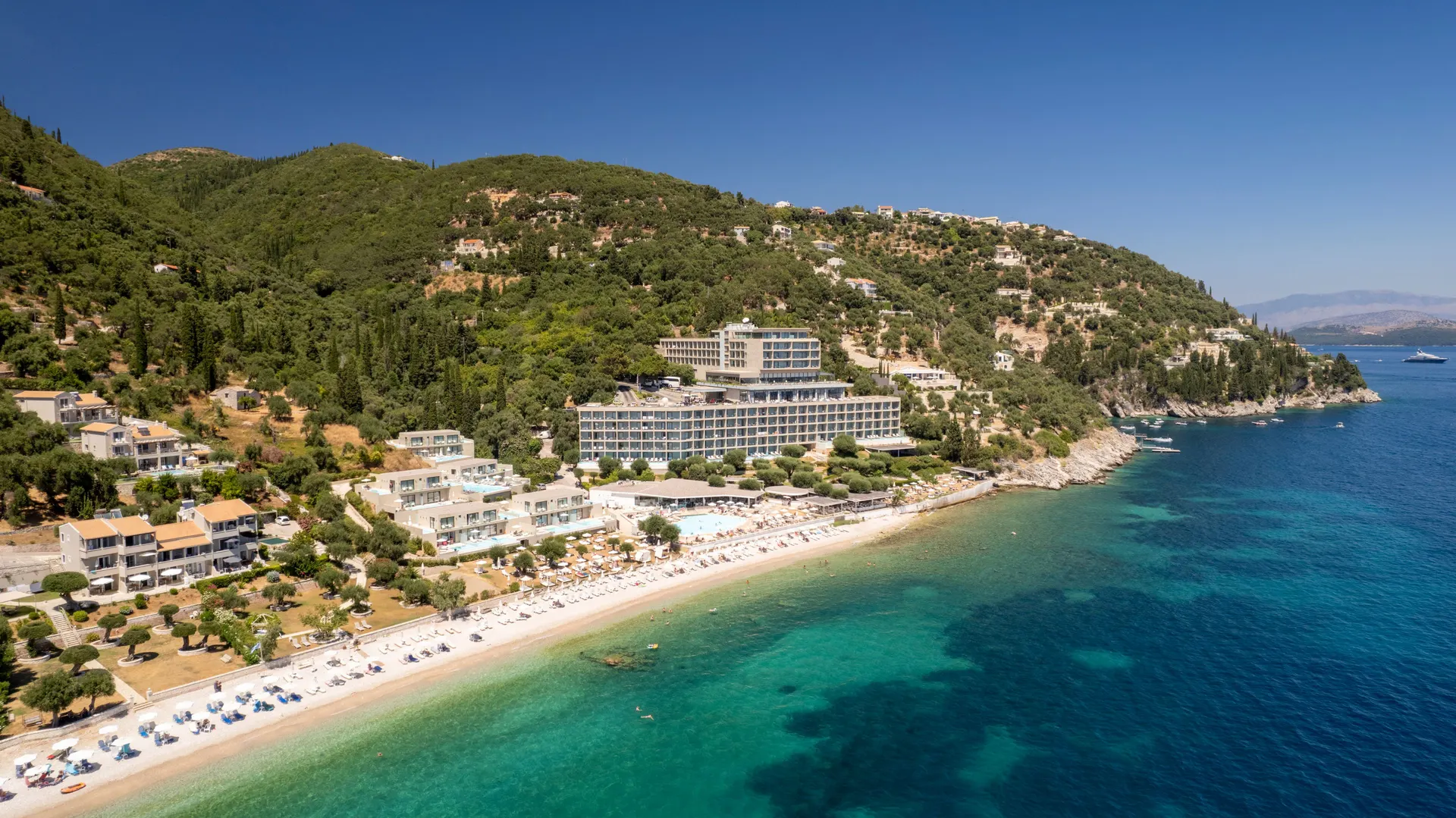 Luchtfoto van het strand van Nissaki aan de noordoostkust van Corfu met hotels tussen het groen