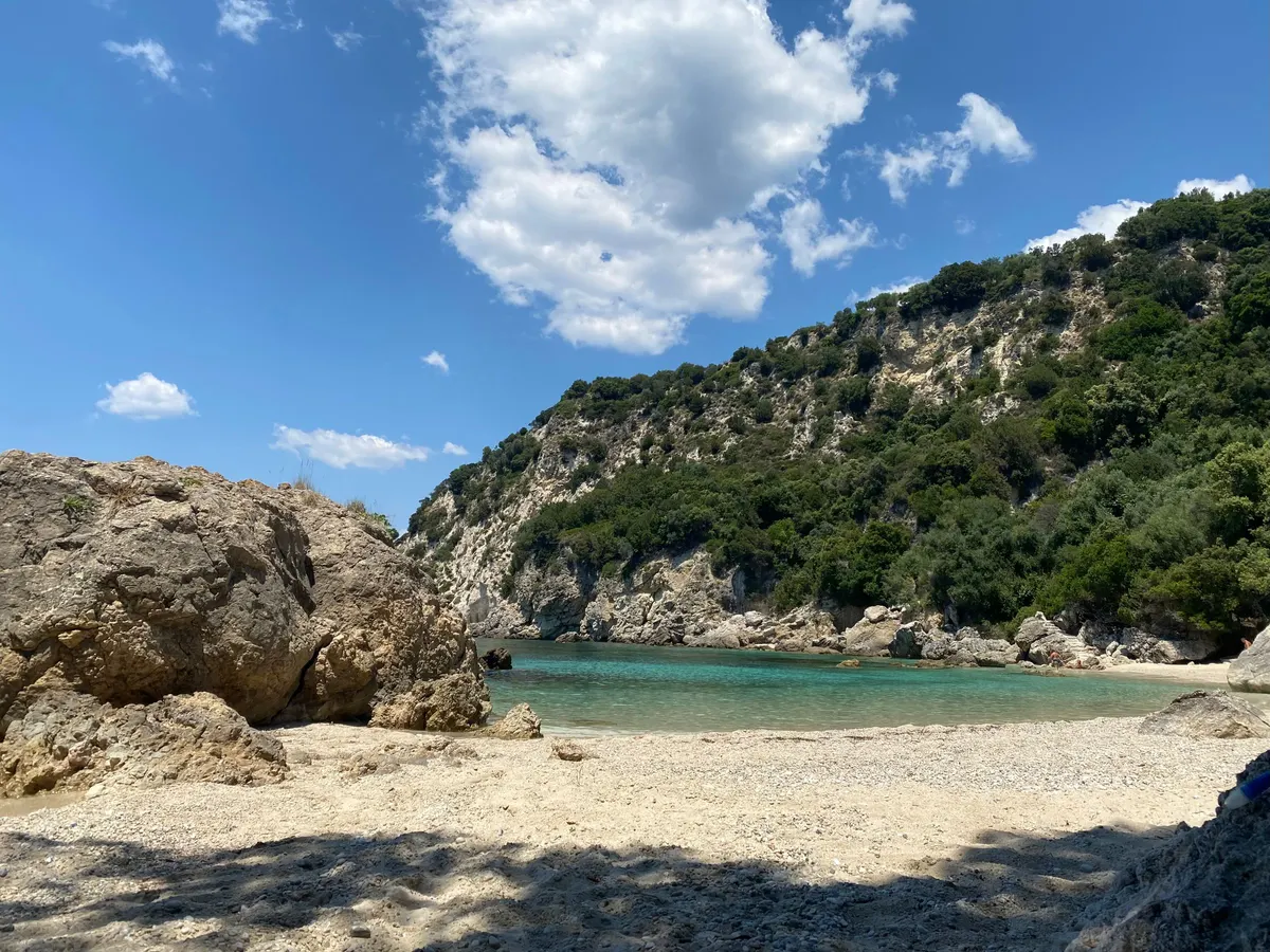 Kleine baai met helder water en beboste rotsen aan de kust van Corfu