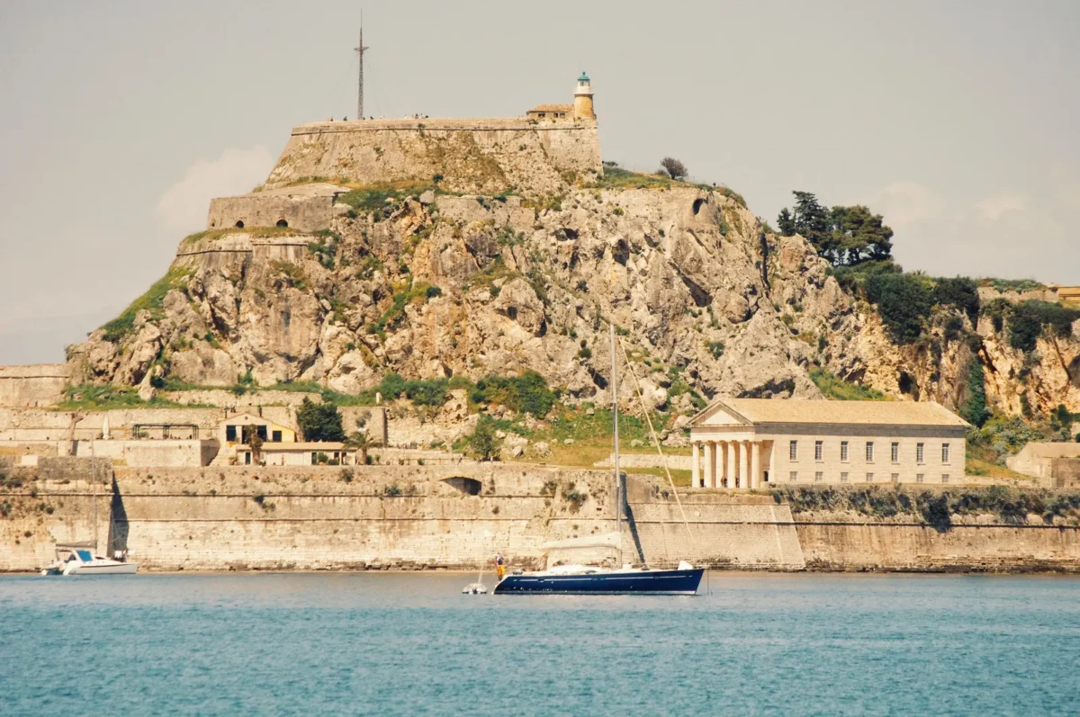 Het Oude Fort van Corfu op een rots aan zee met een zeilboot op de voorgrond
