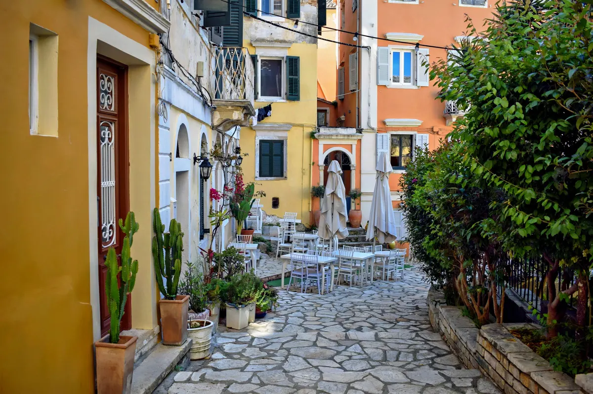 Smal steegje in de oude stad van Corfu met terrasjes en gekleurde gevels
