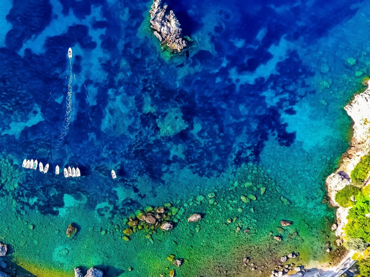 Luchtfoto van turquoise water en bootjes in de baai van Paleokastritsa op Corfu