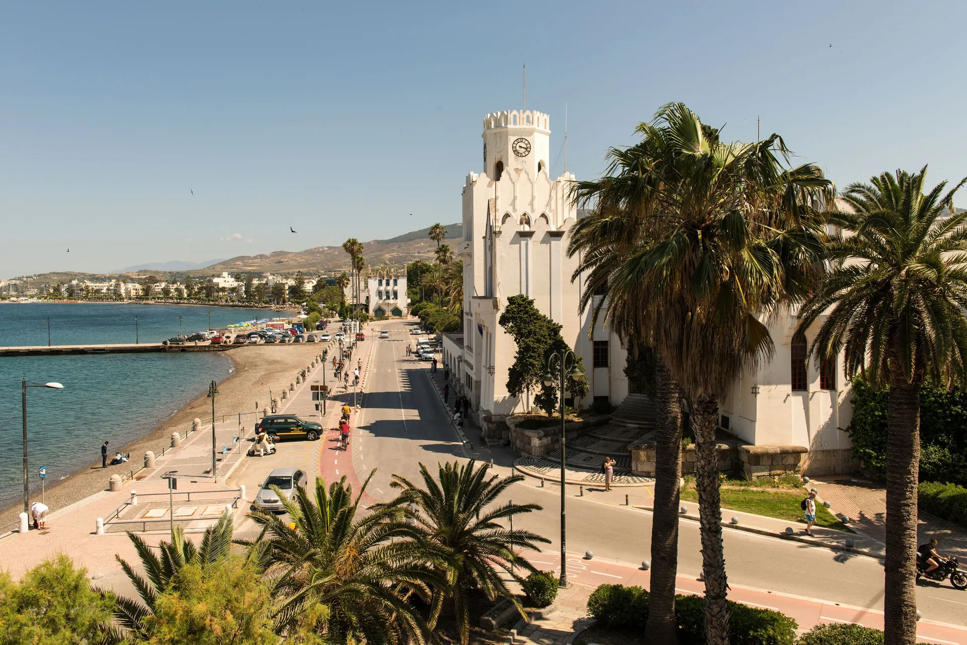 Boulevard van Kos-stad met palmbomen, een historisch gebouw en het stadsstrand