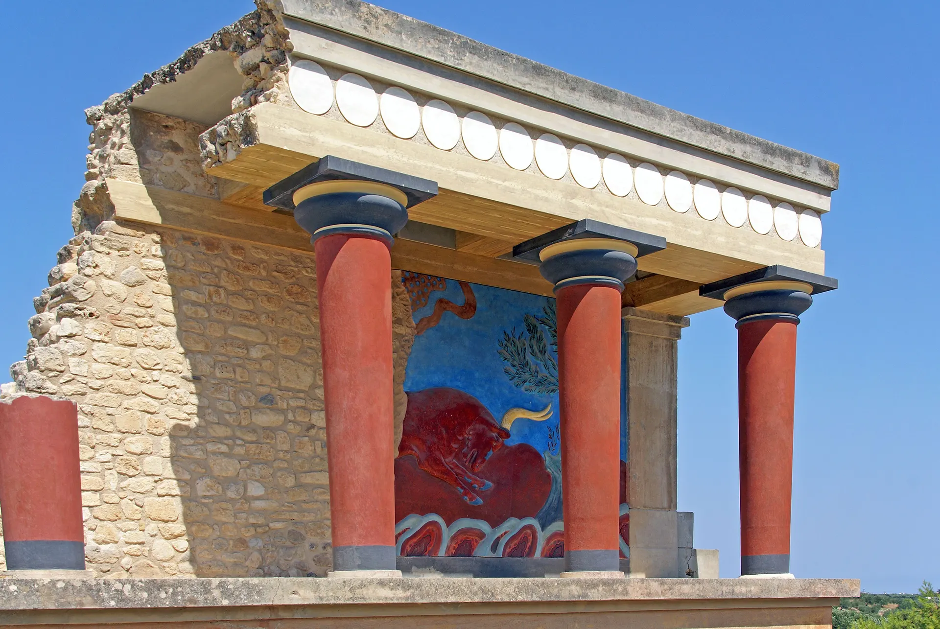 Gereconstrueerde rode zuilen en stierfresco in het Minoïsche paleis van Knossos op Kreta
