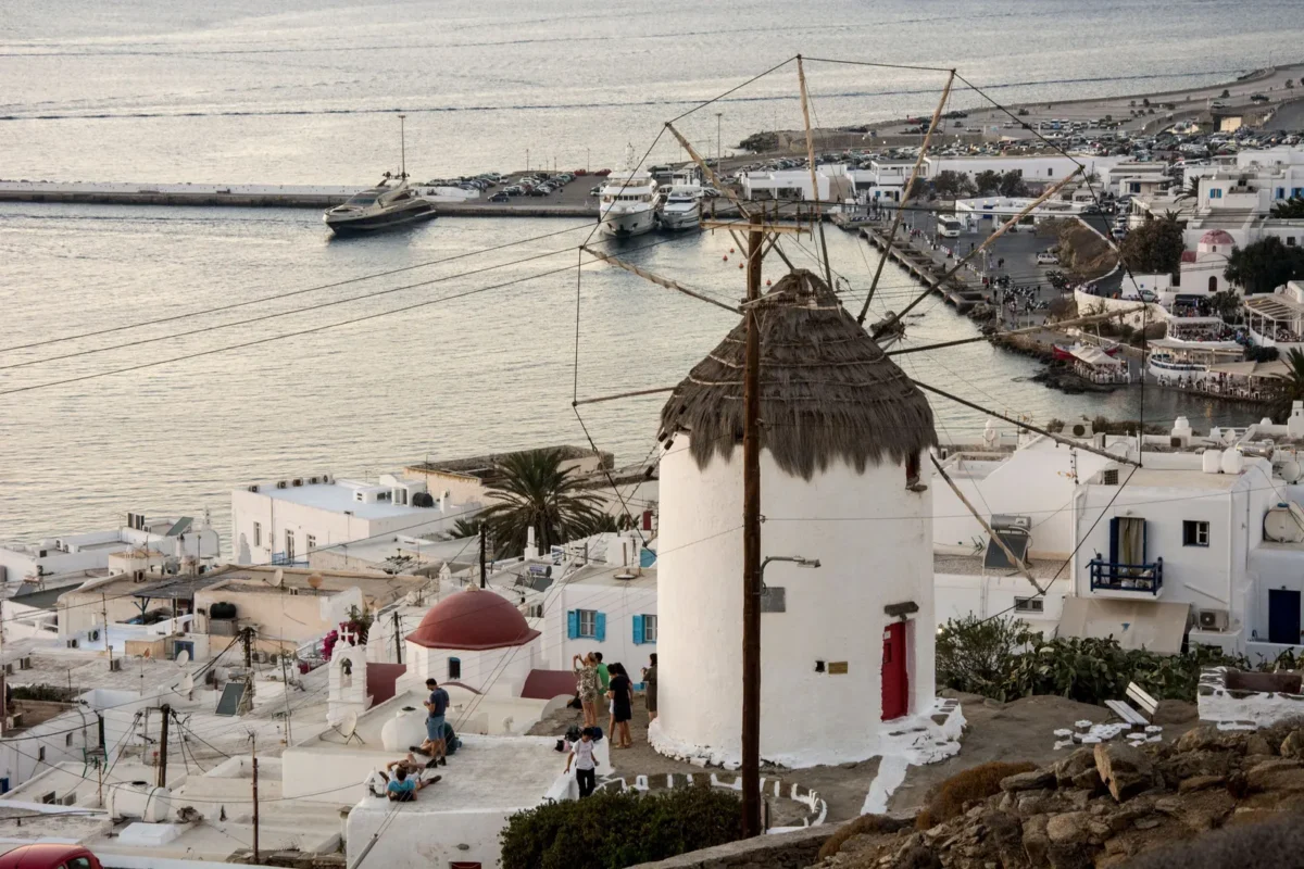 Windmolens van Kato Mili en witte huizen van Mykonos-stad bij zonsondergang
