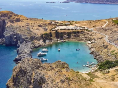 Luchtfoto van de turquoise Sint-Paulusbaai bij Lindos met rotsen en bootjes