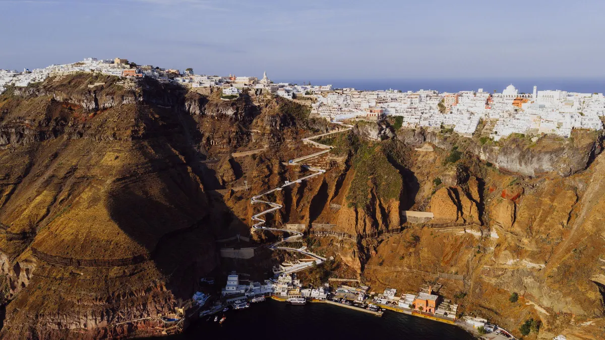 Luchtfoto van Fira op Santorini met witte huizen op de kraterrand en het zigzagpad naar de oude haven
