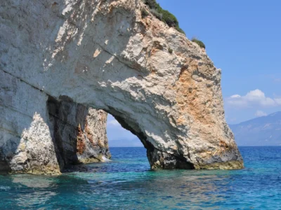 Kalkstenen rotsboog boven helderblauw water bij de Blauwe Grotten van Zakynthos