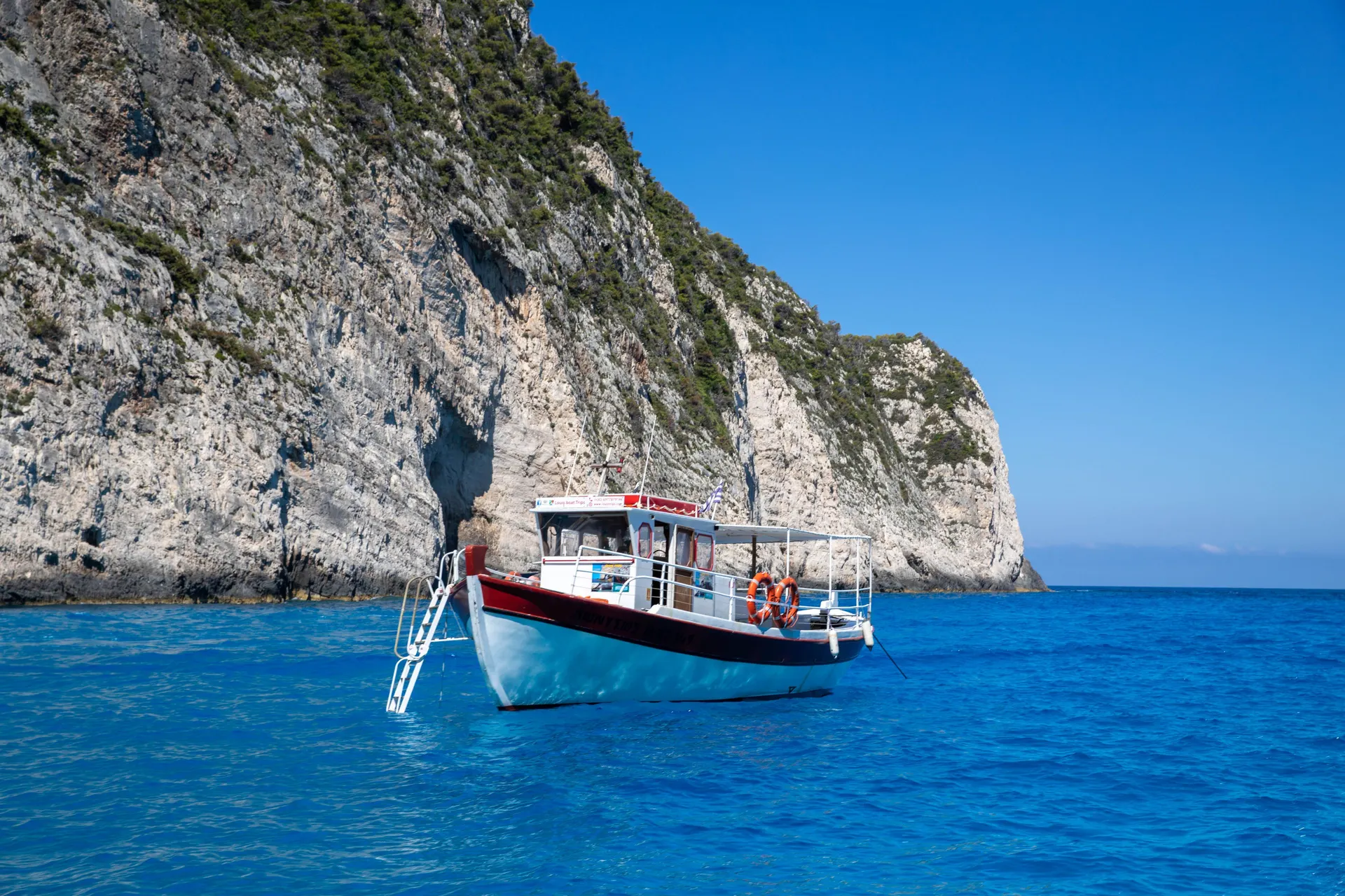 Rondvaartboot bij de witte kliffen van Zakynthos in helderblauw water