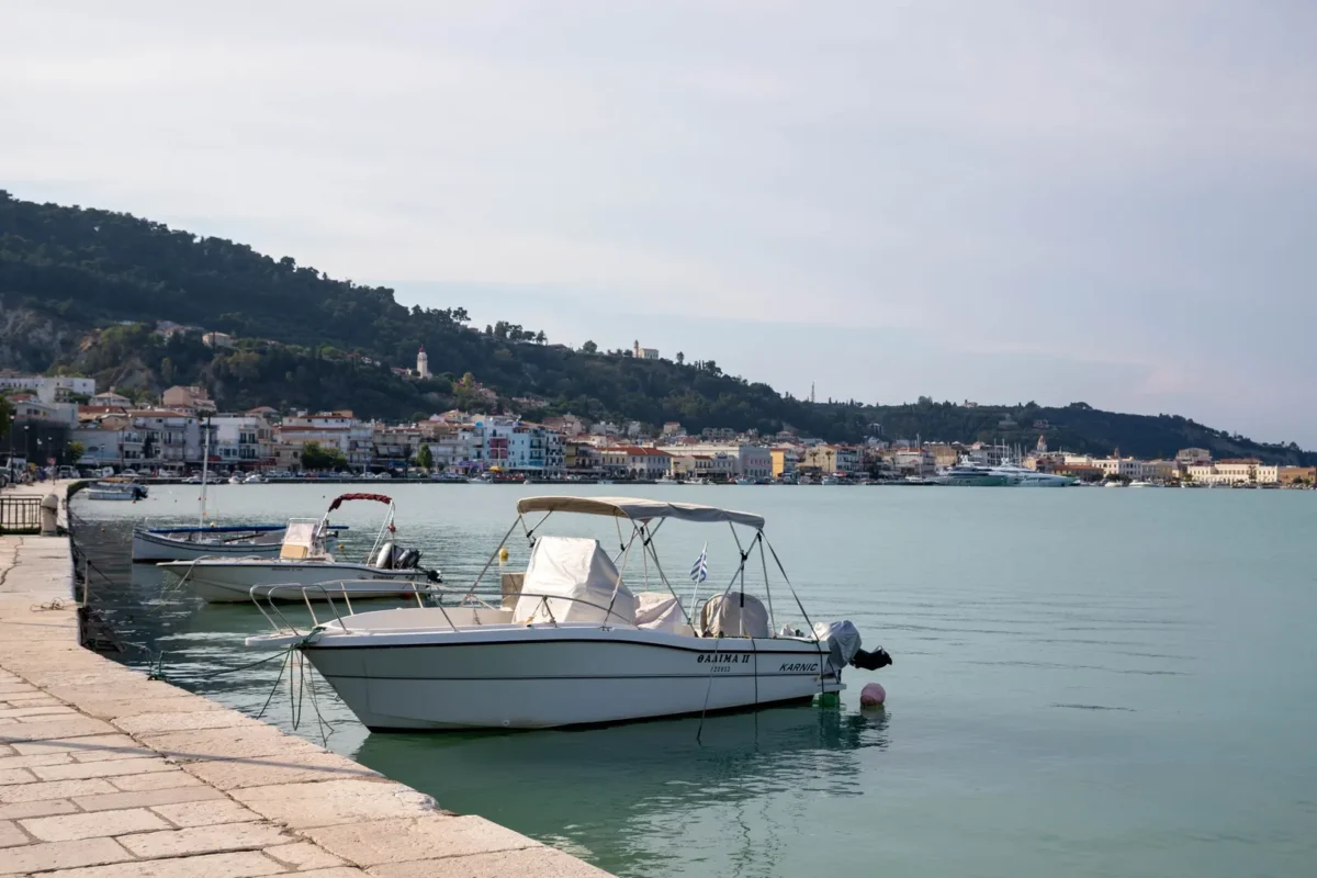 Motorboten aan de kade in een haven op Zakynthos met de kustlijn op de achtergrond