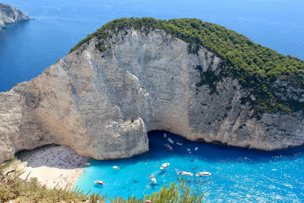 Uitzicht vanaf de klif op de baai van Navagio op Zakynthos met boten in het turquoise water