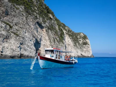 Excursieboot vaart langs de witte kalkkliffen van Zakynthos over helderblauw water