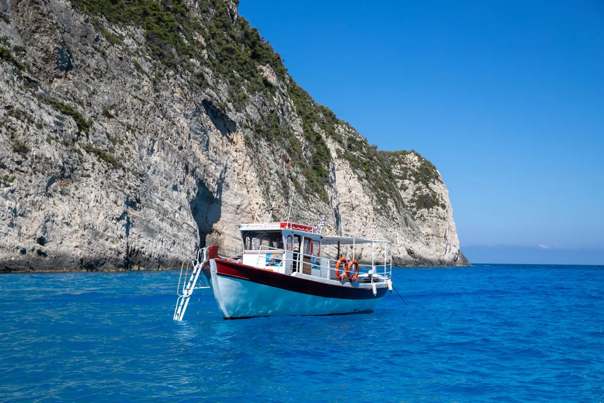 Excursieboot vaart langs de witte kalkkliffen van Zakynthos over helderblauw water