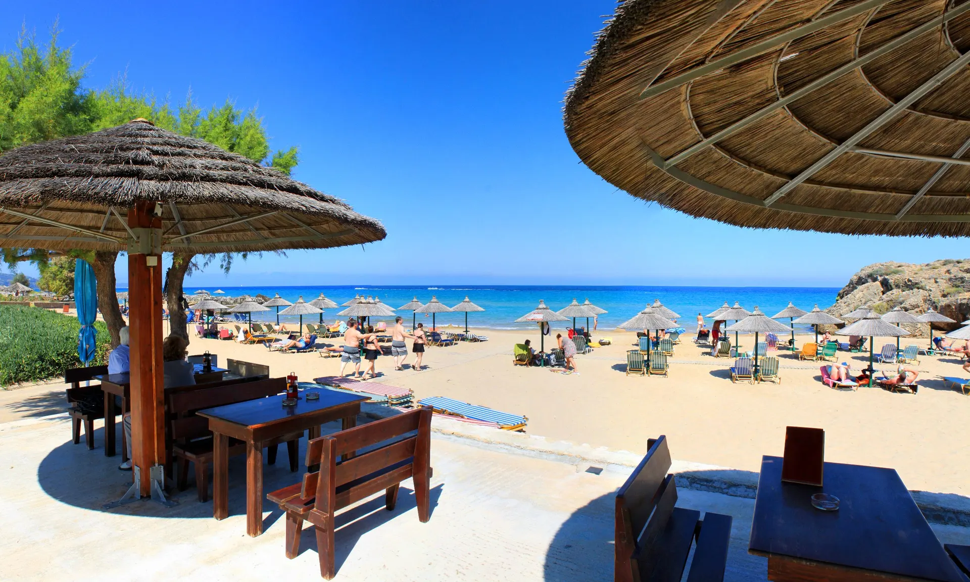 Rieten parasols en een strandbar aan een zandstrand op Zakynthos